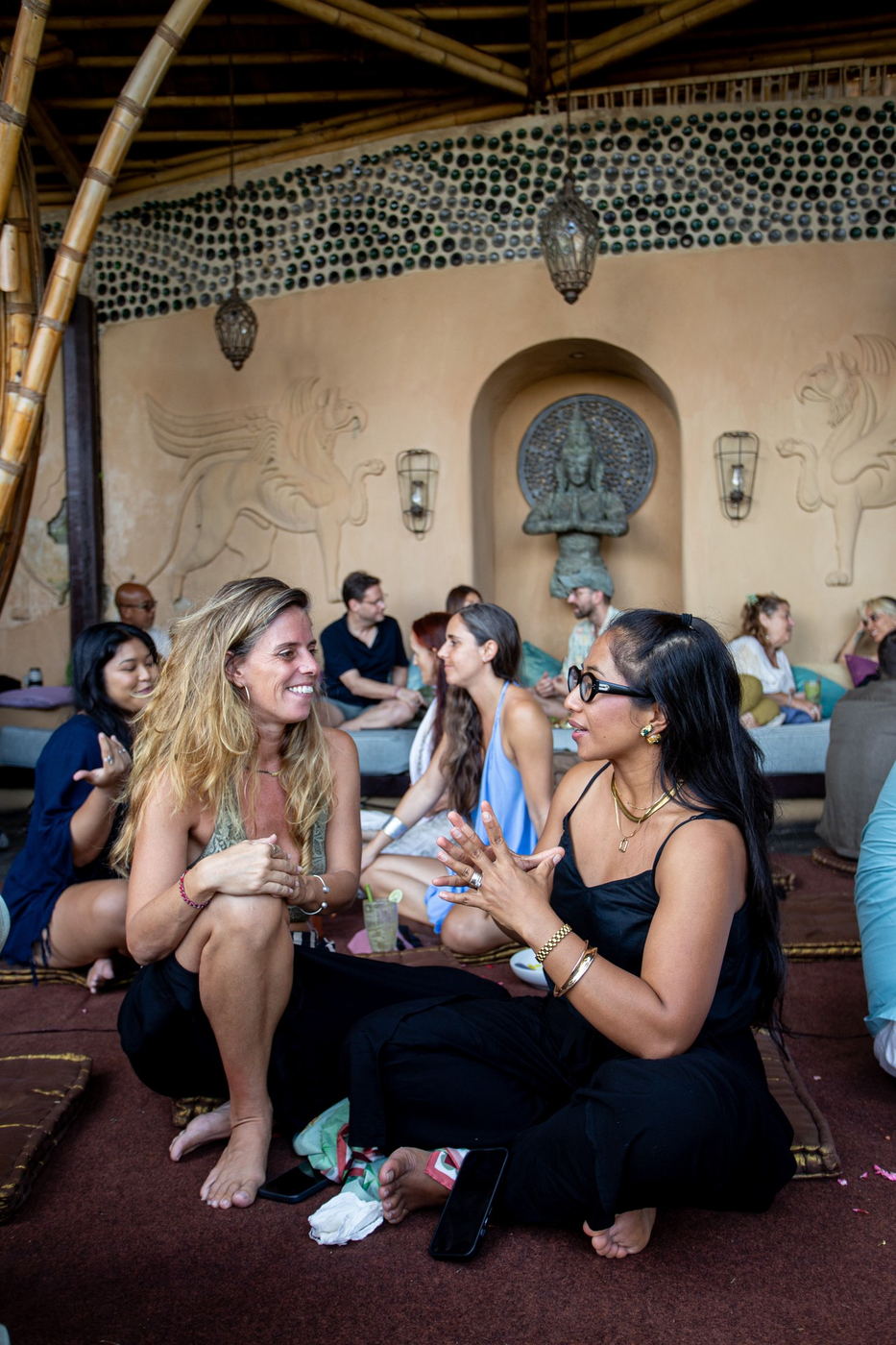 Two women chatting on cushions inside the bamboo venue