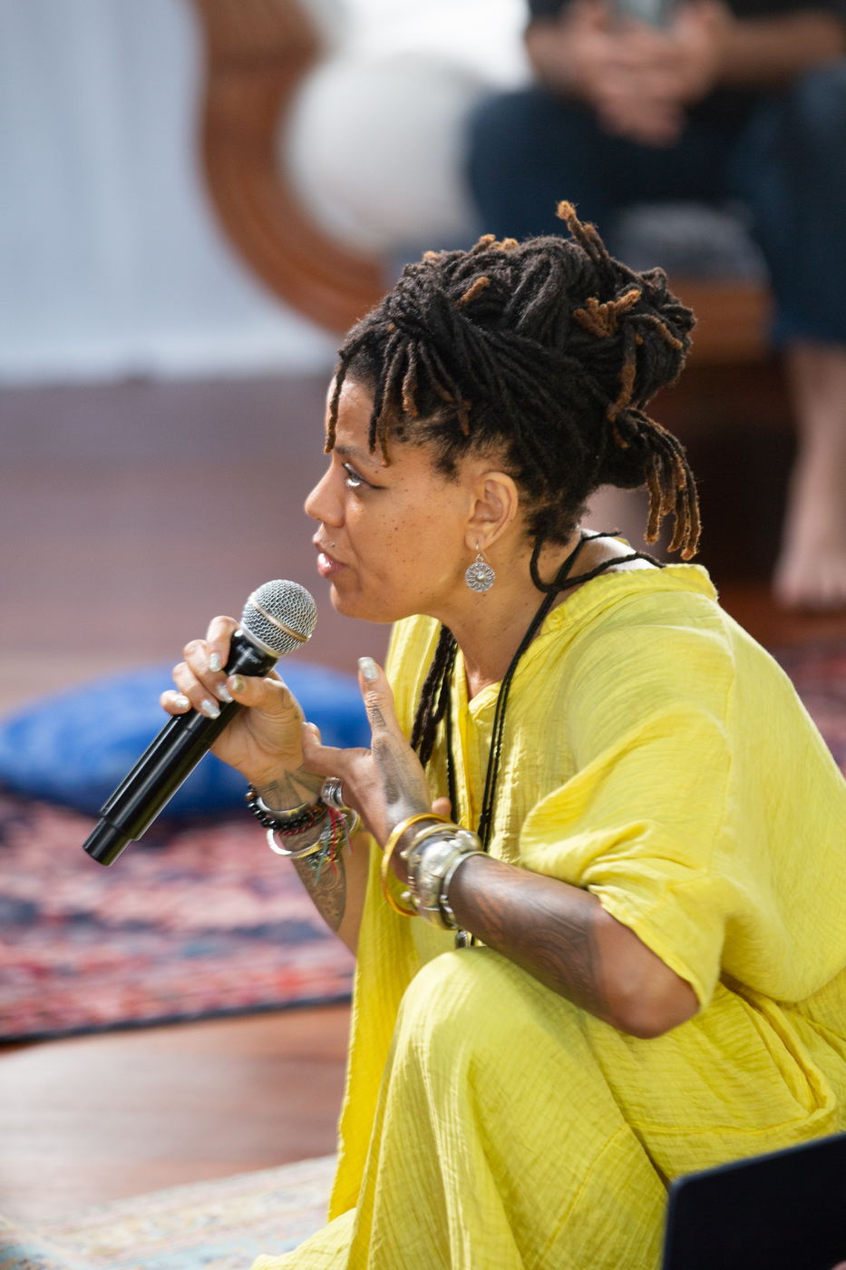 Facilitator speaking into a microphone, seated in the circle