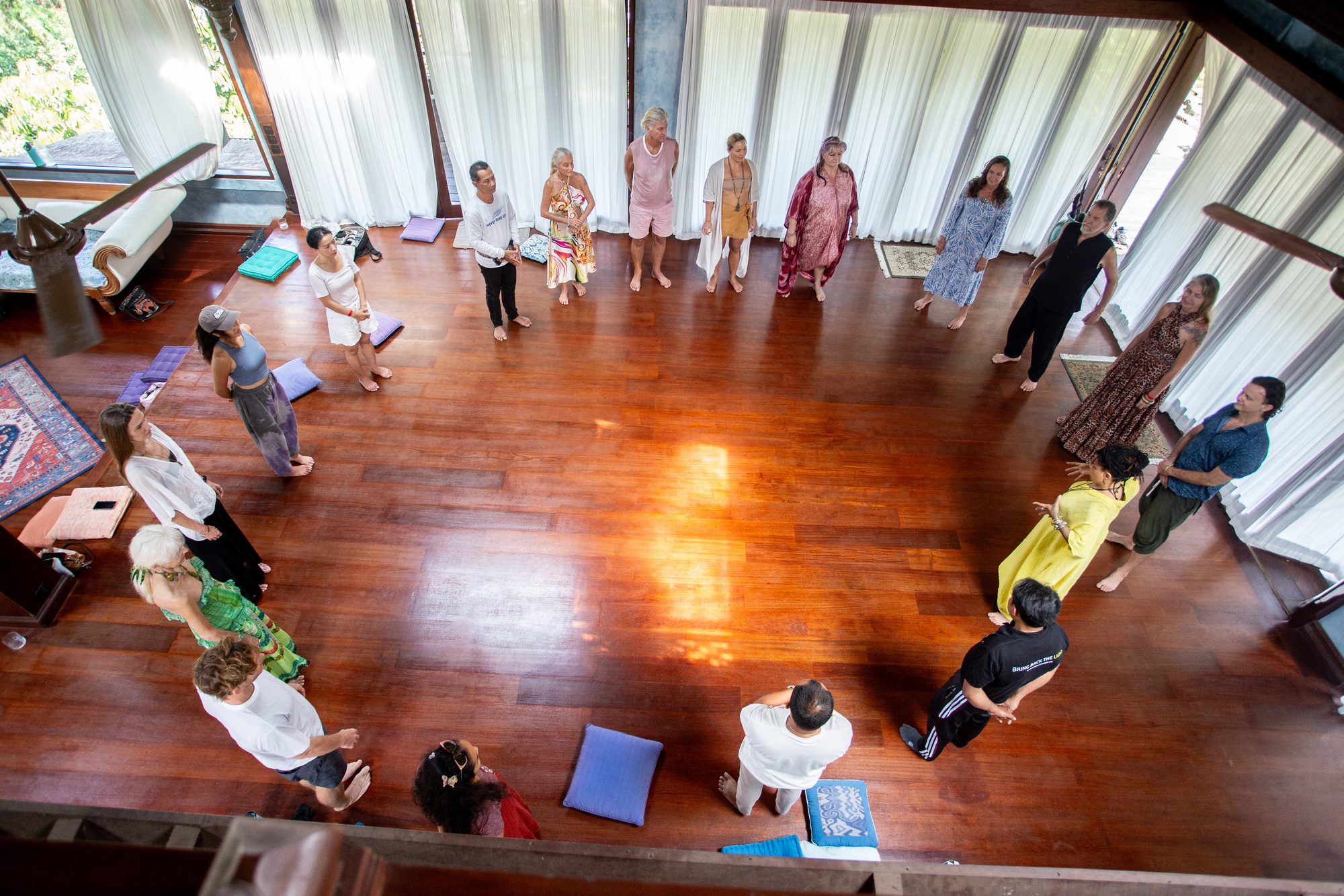 Overhead view of the whole group standing in a wide circle on the timber floor