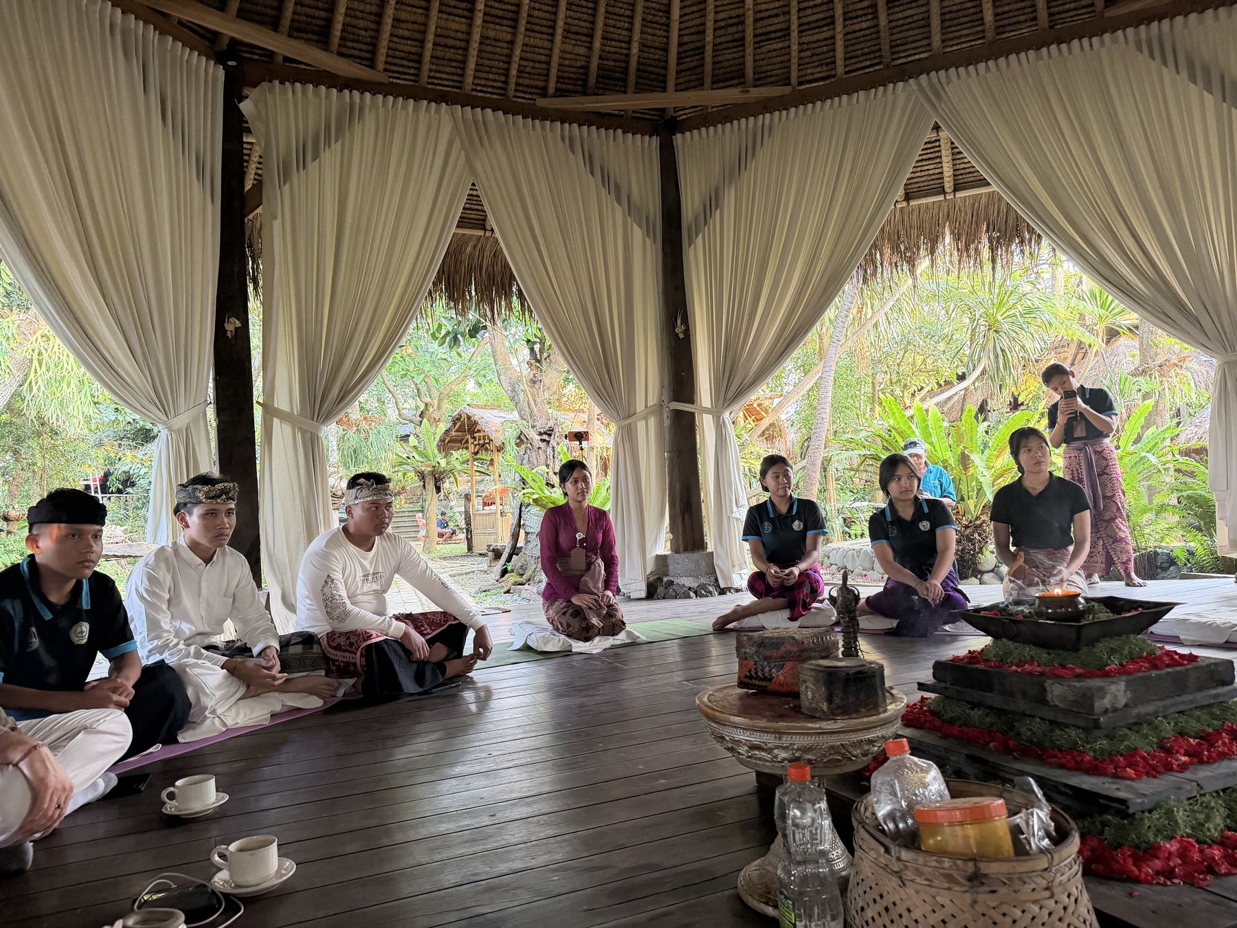Village hosts gathered beside an offering tray of flowers and incense