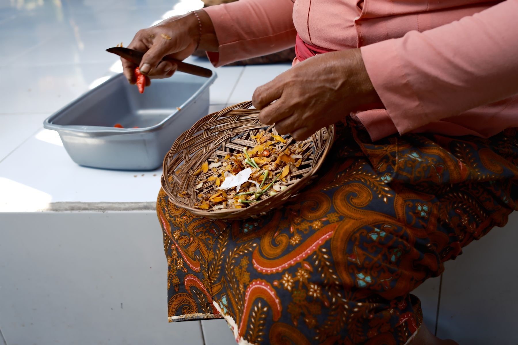A curved knife and a basket of turmeric and chilli peelings