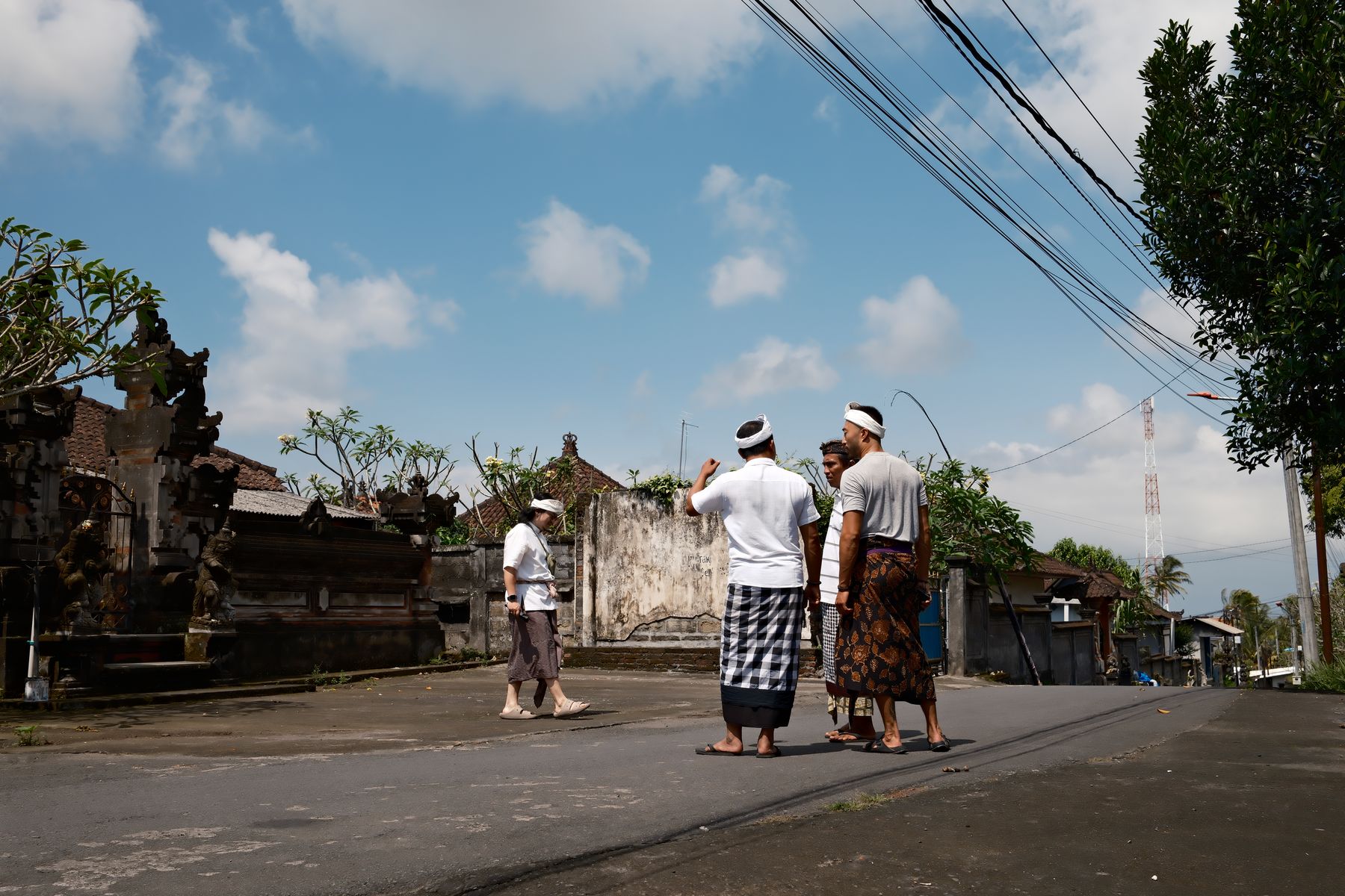 A village road in Bali, visitors walking past the temple gate