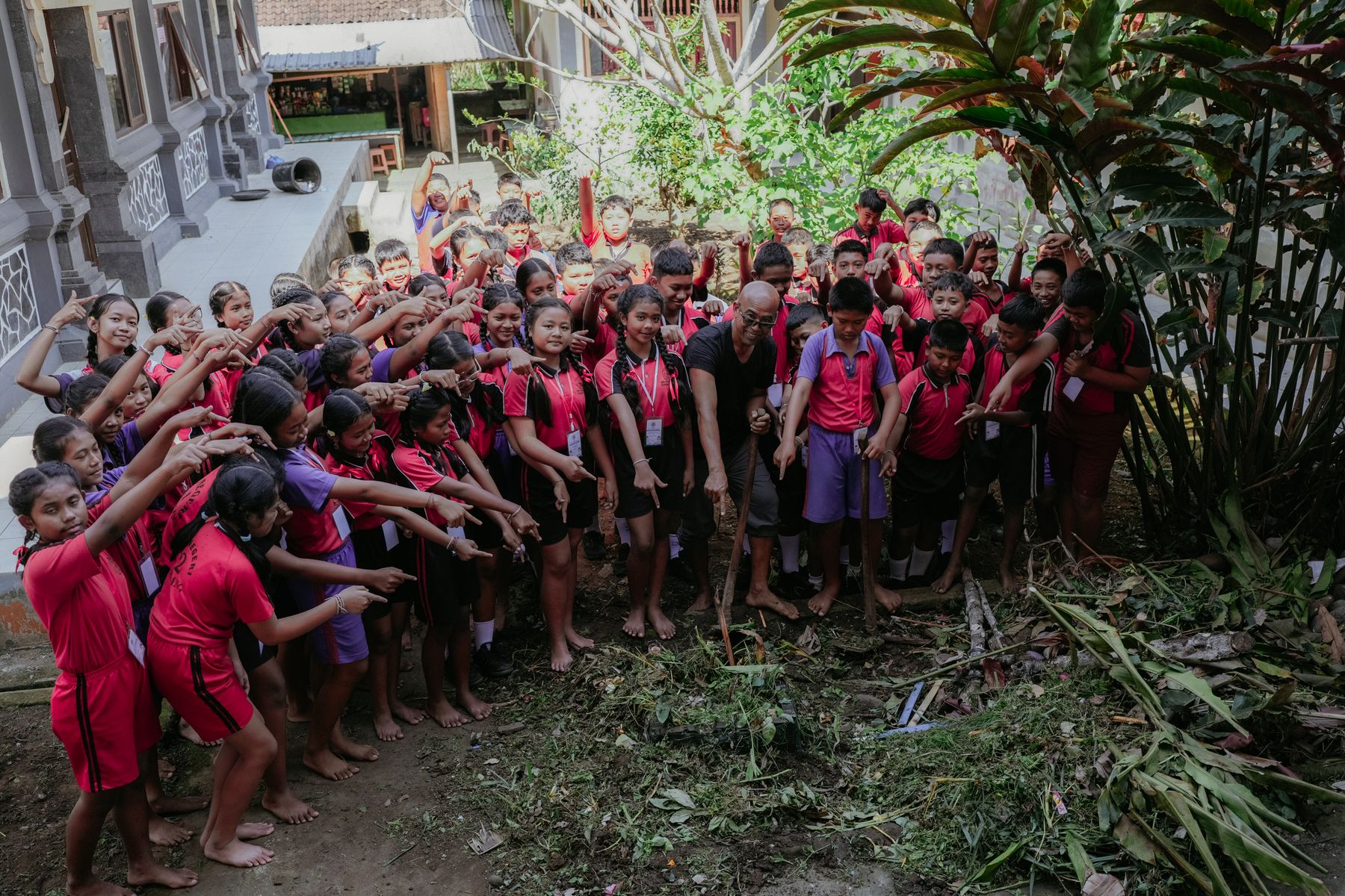Students gathered around a pile of cut green waste in the school grounds